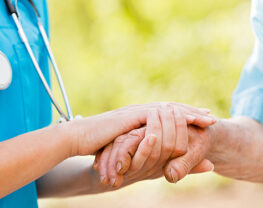 Doctor or nurse holding elderly lady's hands.